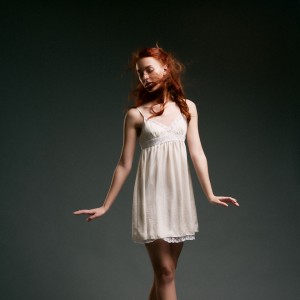 dynamický portrét baletky v bielych šatách a ryšavými vlasmi