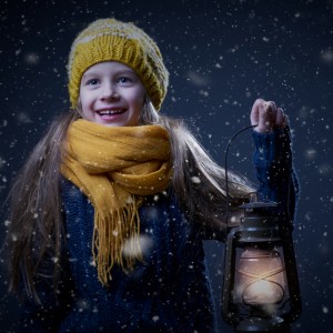 dievčatko so žltou čapicou a žltým šálom držiace petrolejovú lampu, vo vzduchu poletuje sneh